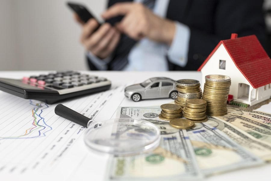 A calculator, coins and household plans laid out while weighing up joining a savings cooperative